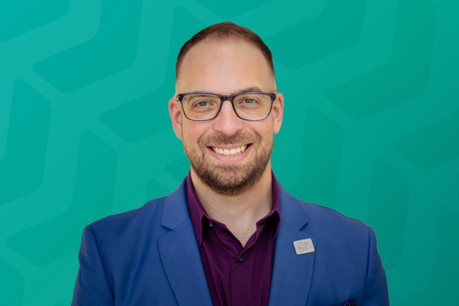 Headshot of Chris Demetriou in front of green chevron background