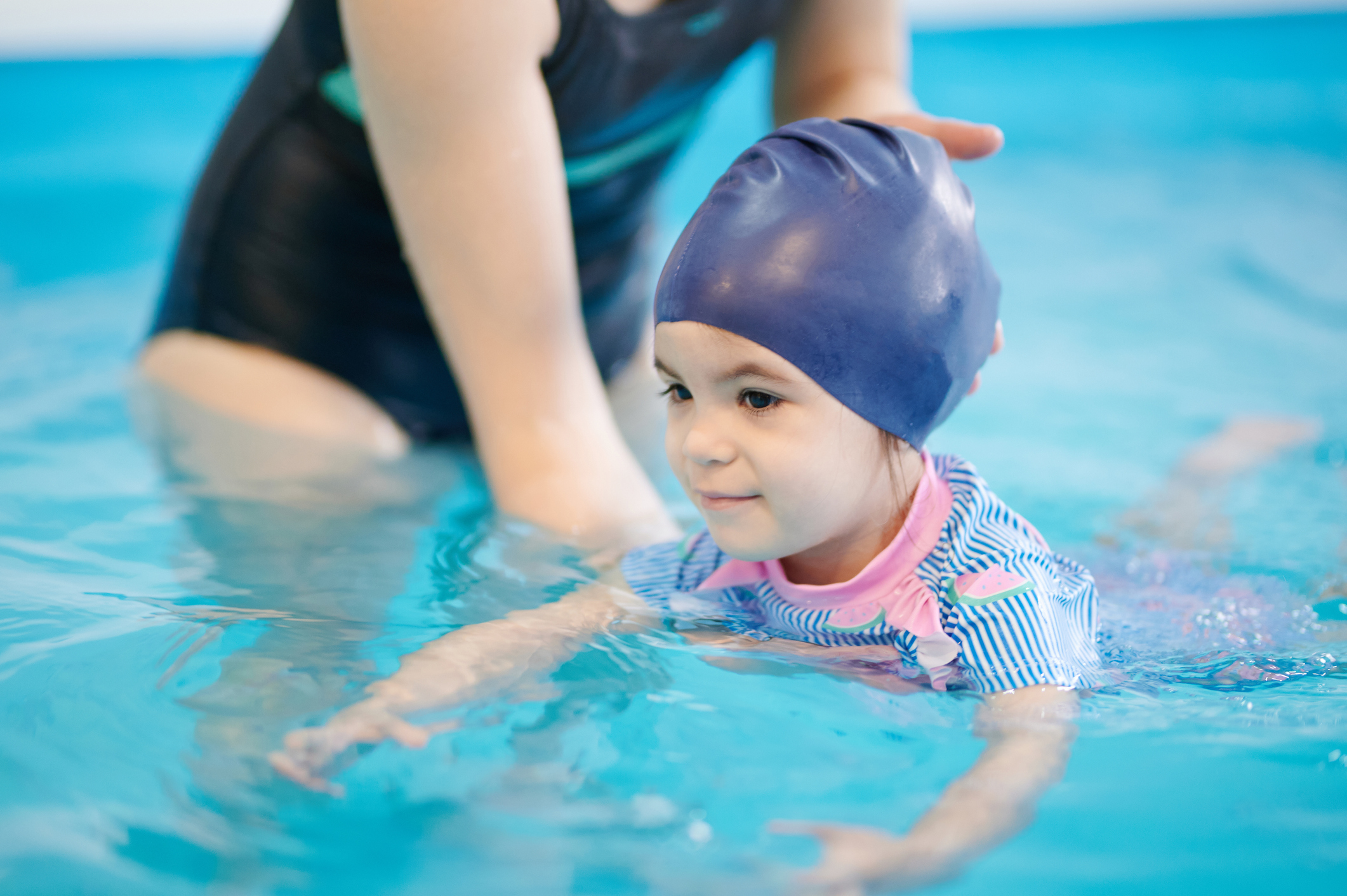 Learning to swim from childhood theme. Kid swimming in blue pool water
