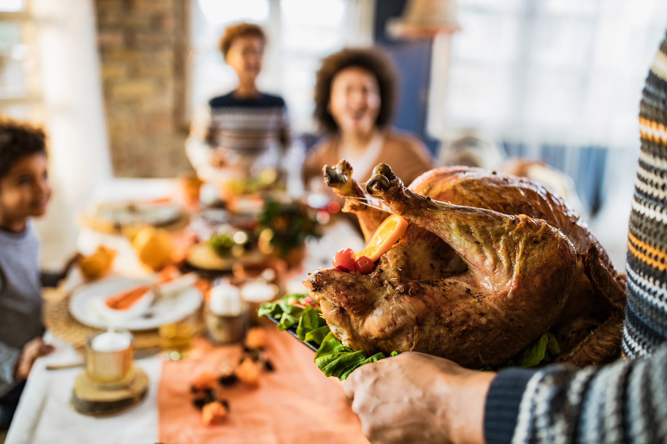 Close up of unrecognizable person carrying Thanksgiving turkey in dining room.