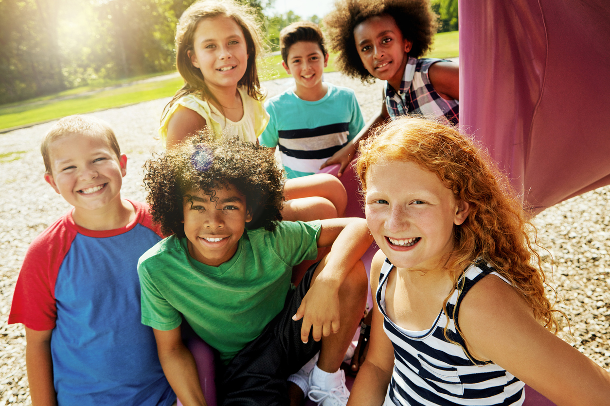 Portrait of a group of diverse and happy kids hanging out together outside