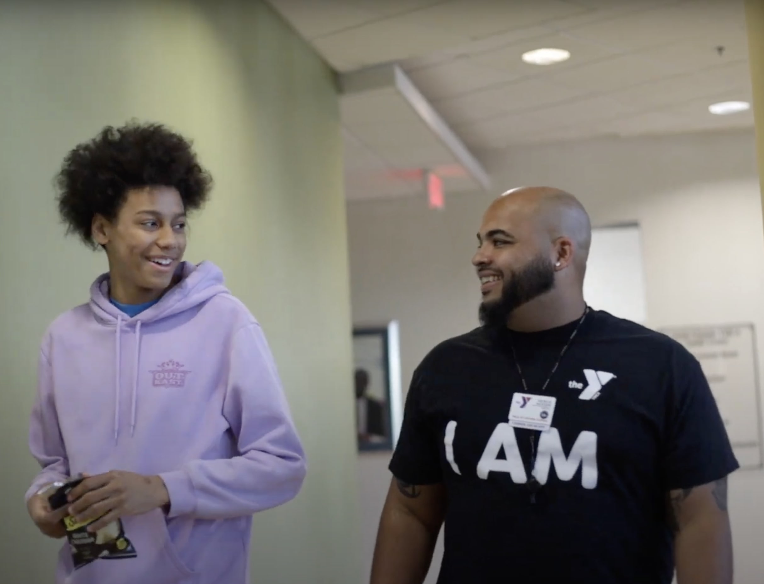 Image of teen and YMCA Youth Development Team Member Patrick Jackson walking through the hallways smiling after a joke